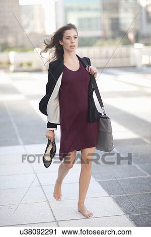 Young businesswoman walking barefoot and carrying high heels View Large Photo Image Stock Image - Young businesswoman walking barefoot and carrying high heels. Fotosearch