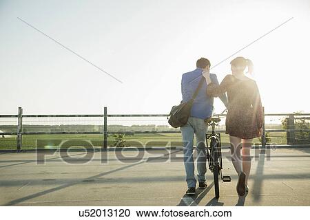 Young couple pushing bicycle in empty parking lot View Large Photo Image Stock Image - Young couple pushing bicycle in empty parking lot. Fotosearch