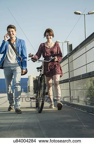 Picture - Young couple pushing bicycle over bridge. Fotosearch