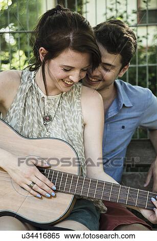 Stock Photography - Young couple serenading on acoustic guitar in park. Fotosearch