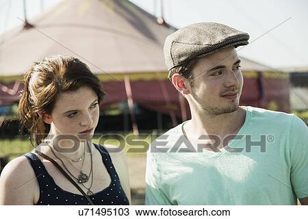 Stock Image - Young couple staring and distracted at funfair. Fotosearch