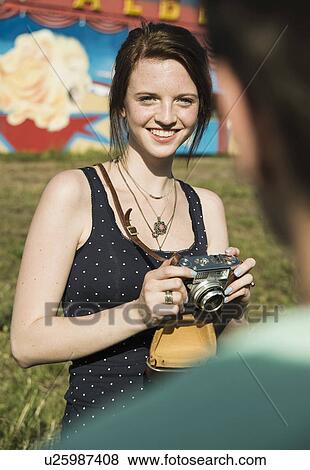 Stock Photo - Young couple taking photographs on SLR camera at funfair. Fotosearch