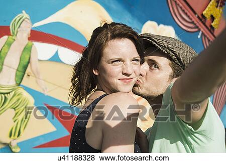 Young couple taking self portrait at funfair View Large Photo Image Stock Photo - Young couple taking self portrait at funfair. Fotosearch