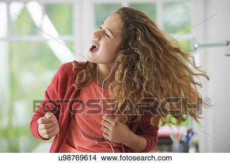 Picture - Young girl wearing headphones, dancing to music. Fotosearch