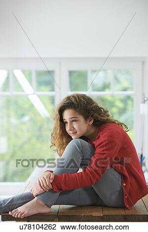 Stock Image - Young girl with brown hair, resting head on knee. Fotosearch