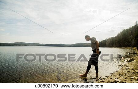 Young male hiker taking apprehensive paddle in lake View Large Photo Image Stock Image - Young male hiker taking apprehensive paddle in lake. Fotosearch