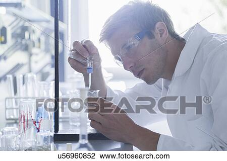 Young male scientist pipetting into beaker in lab View Large Photo Image Stock Image - Young male scientist pipetting into beaker in lab. Fotosearch