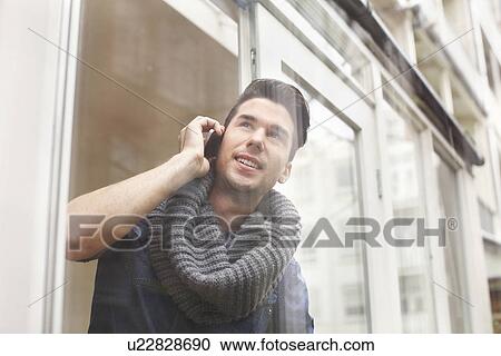 Young man chatting on smartphone behind patio glass View Large Photo Image Stock Image - Young man chatting on smartphone behind patio glass. Fotosearch