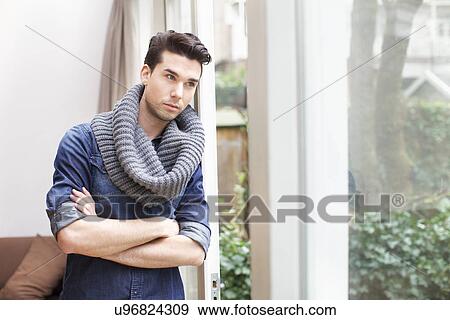 Young man gazing out of window in living room View Large Photo Image Stock Photo - Young man gazing out of window in living room. Fotosearch