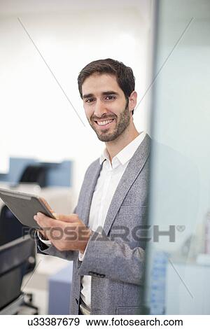 Stock Photo - Young man holding digital tablet. Fotosearch
