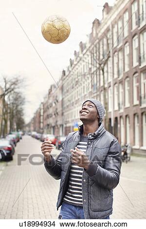 Young man on street throwing soccer ball, Amsterdam, Netherlands View Large Photo Image Picture - Young man on street throwing soccer ball, Amsterdam, Netherlands. Fotosearch