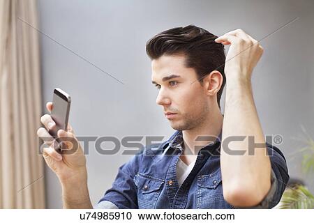 Young man taking selfie on smartphone in living room View Large Photo Image Stock Image - Young man taking selfie on smartphone in living room. Fotosearch