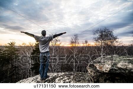 Young man with arms outstretched on top of rock formation at sunset View Large Photo Image Stock Image - Young man with arms outstretched on top of rock formation at sunset. Fotosearch