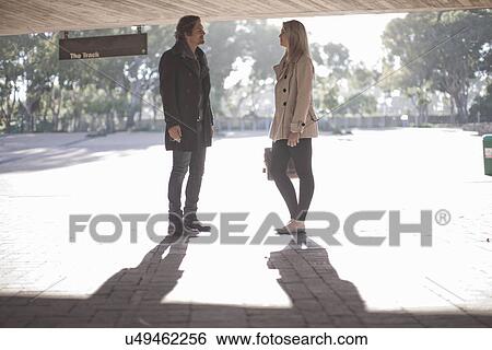 Stock Photograph - Young woman chatting to mid adult man in city underpass. Fotosearch