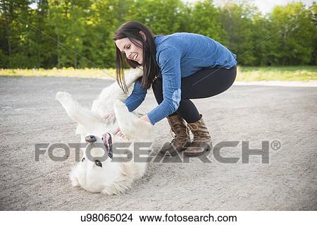 Young woman petting golden retriever on roadside View Large Photo Image Picture - Young woman petting golden retriever on roadside. Fotosearch