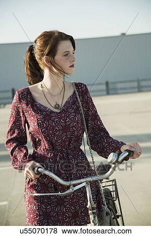 Young woman pushing bicycle in empty parking lot View Large Photo Image Stock Photo - Young woman pushing bicycle in empty parking lot. Fotosearch