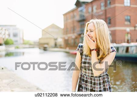 Stock Photo - Young woman standing by canal, Leeds, England. Fotosearch