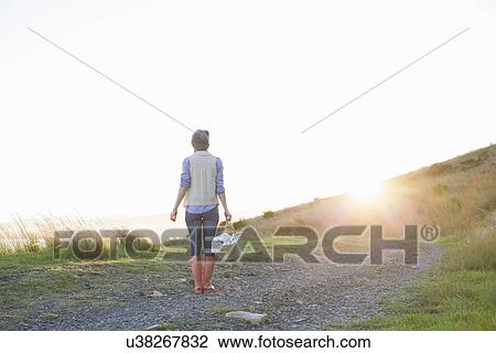 Young woman standing on hill at sunset View Large Photo Image Stock Image - Young woman standing on hill at sunset. Fotosearch