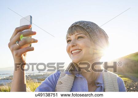 Stock Image - Young woman taking selfie with smartphone. Fotosearch