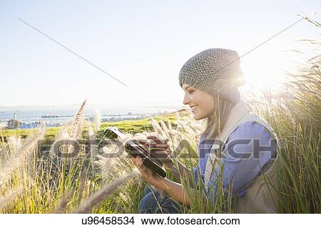 Picture - Young woman using digital tablet in fields. Fotosearch