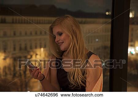 Young woman using smartphone in hotel room, Vienna, Austria View Large Photo Image Stock Photograph - Young woman using smartphone in hotel room, Vienna, Austria. Fotosearch
