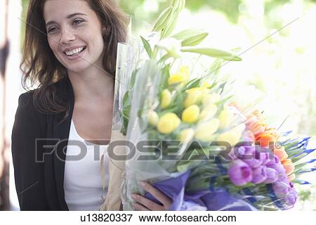 Stock Photo - Young woman with bunches of tulips on street. Fotosearch