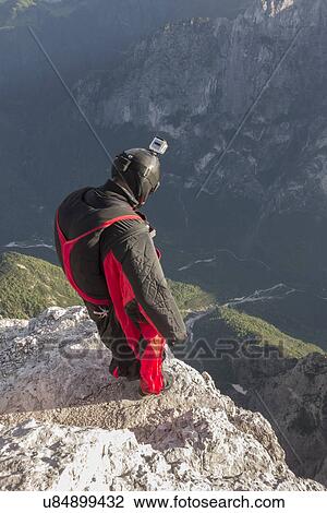 Stock Image - BASE jumper on mountain edge, Alleghe, Dolomites, Italy. Fotosearch