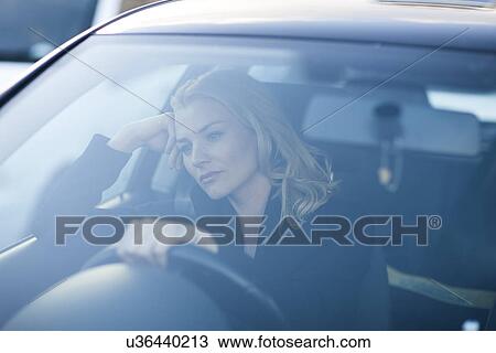 Stock Image - Bored businesswoman staring whilst driving in city traffic jam. Fotosearch