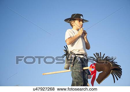 Stock Photo - Boy dressed as cowboy fastening hat. Fotosearch