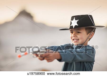 Boy dressed as cowboy sheriff holding pointing toy guns in sand dunes View Large Photo Image Stock Image - Boy dressed as cowboy sheriff holding pointing toy guns in sand dunes. Fotosearch