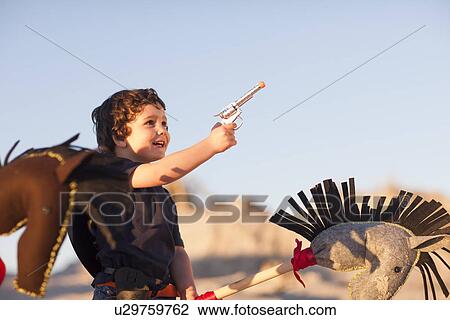 Boy dressed as cowboy with hobby horse and toy gun in sand dunes View Large Photo Image Stock Image - Boy dressed as cowboy with hobby horse and toy gun in sand dunes. Fotosearch