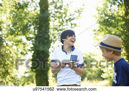 Stock Image - Boy holding fish, laughing. Fotosearch