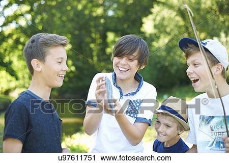 Stock Image - Boy holding fish with friends. Fotosearch