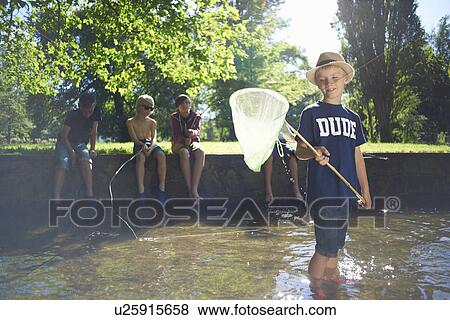 Boy holding fishing net with friends in background View Large Photo Image Stock Photo - Boy holding fishing net with friends in background. Fotosearch