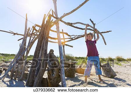 Boy lifting driftwood to construct shelter, Caleri Beach, Veneto, Italy View Large Photo Image Stock Image - Boy lifting driftwood to construct shelter, Caleri Beach, Veneto, Italy. Fotosearch