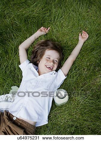 Boy lying on grass laughing View Large Photo Image Stock Image - Boy lying on grass laughing. Fotosearch