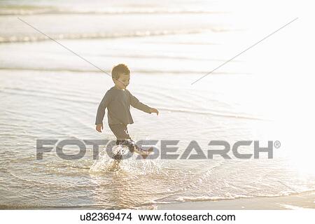 Picture - Boy paddling and splashing in the sea. Fotosearch