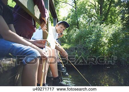 Stock Photo - Boys sitting on bridge, fishing. Fotosearch