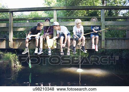 Boys sitting on bridge, fishing View Large Photo Image Stock Photo - Boys sitting on bridge, fishing. Fotosearch