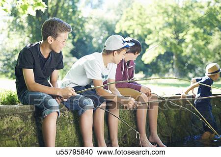 Stock Image - Boys sitting on wall, fishing. Fotosearch