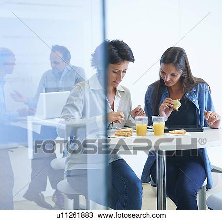Stock Image - Business people having discussion over lunch. Fotosearch