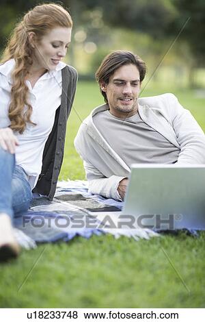 Businessman and female colleague looking at laptop in park View Large Photo Image Stock Photo - Businessman and female colleague looking at laptop in park. Fotosearch