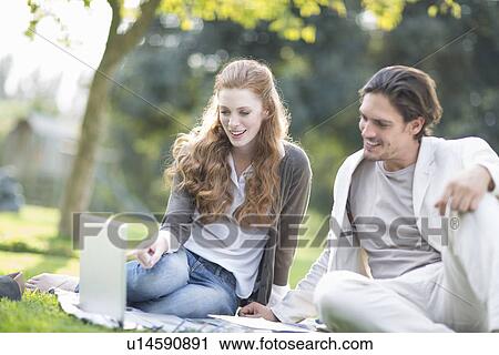 Businessman and female colleague using laptop in park View Large Photo Image Stock Image - Businessman and female colleague using laptop in park. Fotosearch