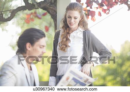 Stock Image - Businessman reading newspaper before informal meeting in garden. Fotosearch