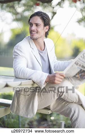 Businessman reading newspaper in park View Large Photo Image Picture - Businessman reading newspaper in park. Fotosearch