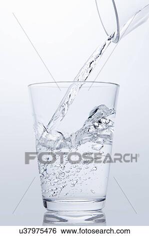 Stock Photograph - Clear water pouring from jug into drinking glass. Fotosearch