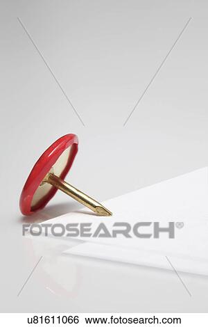Stock Photograph - Close up of drawing pin on the corner of blank paper. Fotosearch