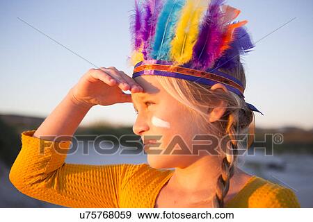 Close up of girl dressed as native american in feather headdress with hand shading eyes View Large Photo Image Stock Photo - Close up of girl dressed as native american in feather headdress with hand shading eyes. Fotosearch