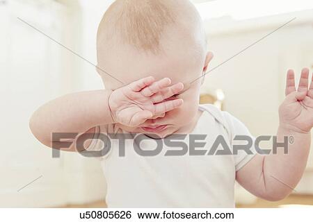 Stock Photograph - Close up of tired baby boy with hand covering eyes. Fotosearch