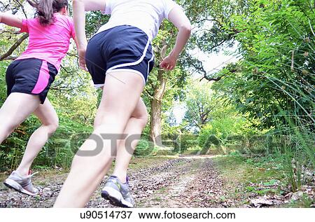 Close up of two young women runners running along forest track View Large Photo Image Stock Photo - Close up of two young women runners running along forest track. Fotosearch
